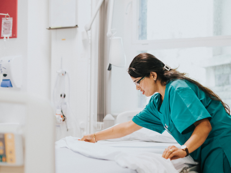 Female nurse making a bed in a hospital room