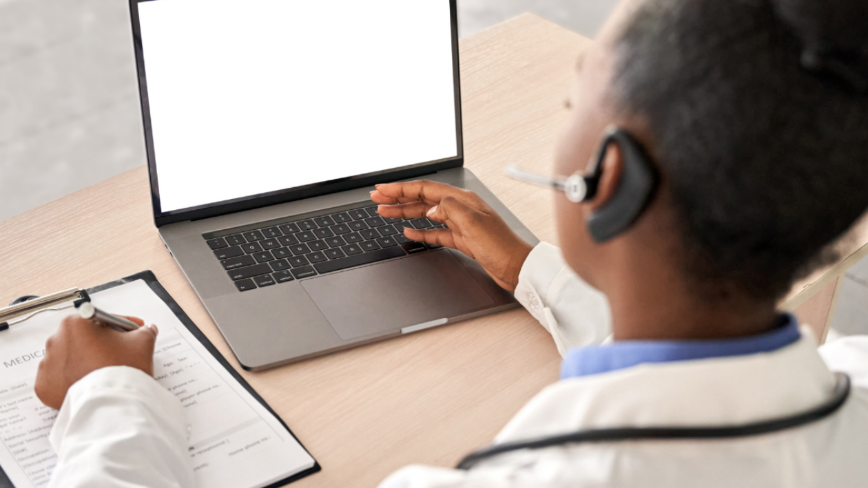 NHS professional looking at laptop at a desk