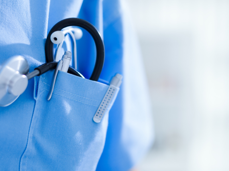 A close-up of the pocket of a medical uniform with a stethoscope and a pen showing.