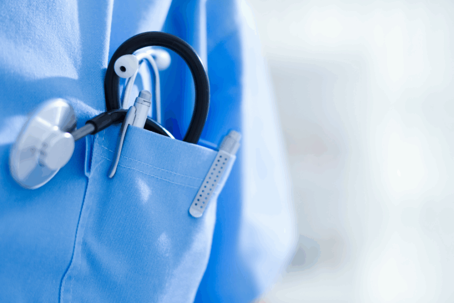 A close-up of the pocket of a medical uniform with a stethoscope and a pen showing.
