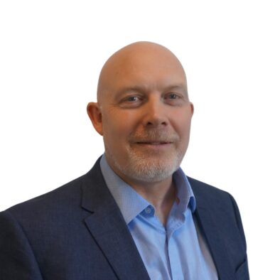 A portrait photo of Martin, wearing a blue shirt and a black jacket, smiling at the camera.