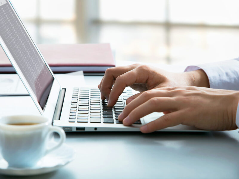 A close up of a man typing on his laptop